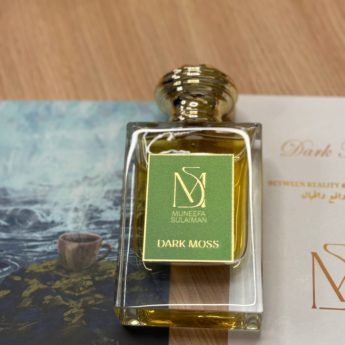 Muneefa Sulaiman Dark Moss bottle beside the house card