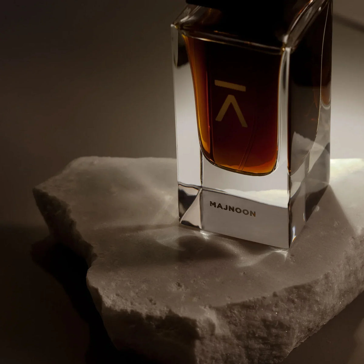 Azman Majnoon parfum bottle lit on white stone