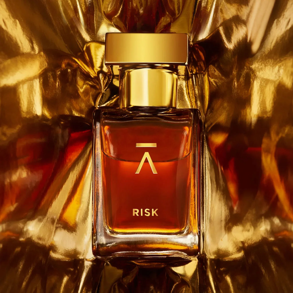 Azman Risk parfum bottle against crumpled gold foil