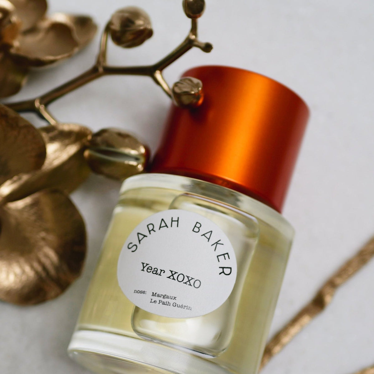Sarah Baker Year XOXO label close up with a gold orchid